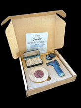 Load image into Gallery viewer, A gift box open to reveal its contents, which include a smoker, metal tin with wood chips, mini butane torch, carry bag, and smoker screens.